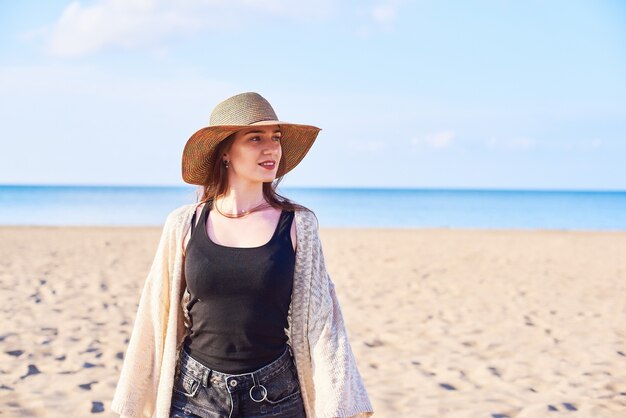 Hermosa mujer joven en sombrero de paja en la playa