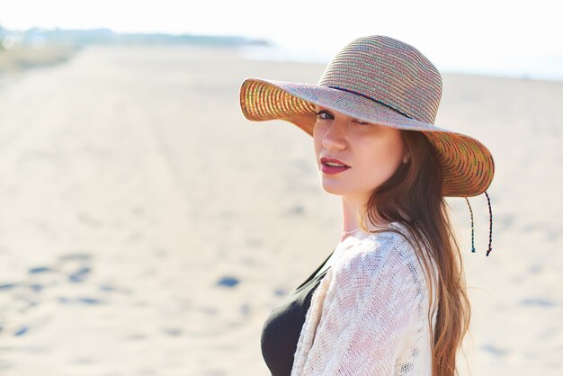 Hermosa mujer joven en sombrero de paja en la playa