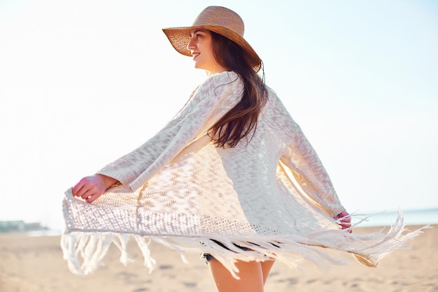 Hermosa mujer joven en sombrero de paja en la playa