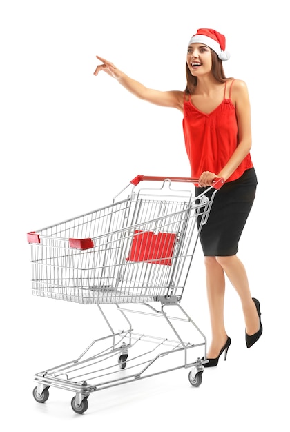 Foto hermosa mujer joven con sombrero de santa claus y con carro vacío. concepto de compras navideñas