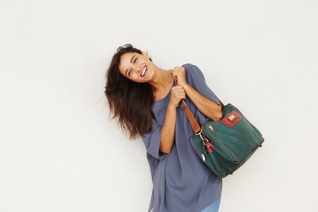 Hermosa mujer joven sonriendo con bolsa contra la pared blanca