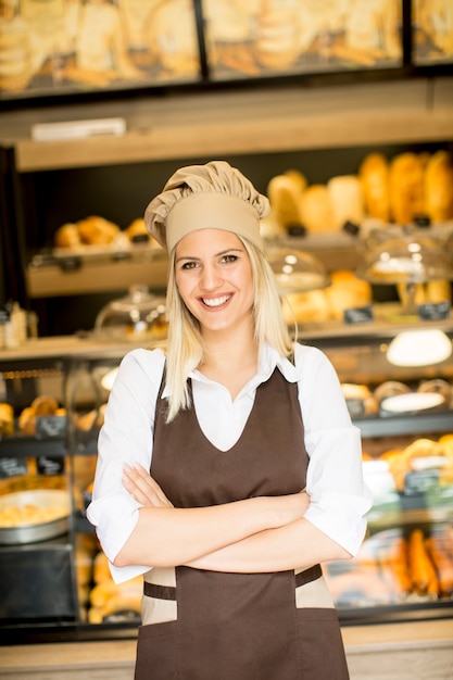 Hermosa mujer joven sonriendo posando con confianza en su panadería