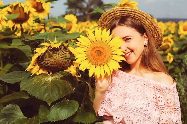 Hermosa mujer joven sonriente en una camisa blanca se encuentra en el campo entre los girasoles