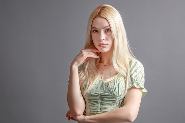 Hermosa mujer joven sonriente con el concepto de belleza natural de la cara de la piel perfecta aislada en el fondo gris del estudio