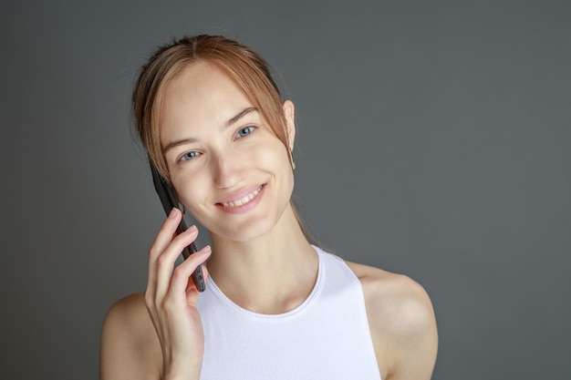 Hermosa mujer joven sonriente con el concepto de belleza natural de la cara de la piel perfecta aislada en el fondo gris del estudio