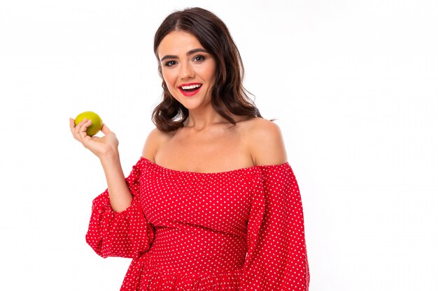 Hermosa mujer joven con una sonrisa perfecta, gafas de sol y tiene una manzana verde y sonrisas, aislado