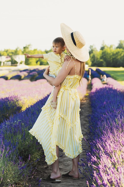 Hermosa mujer joven y su lindo hijito en el campo de lavanda