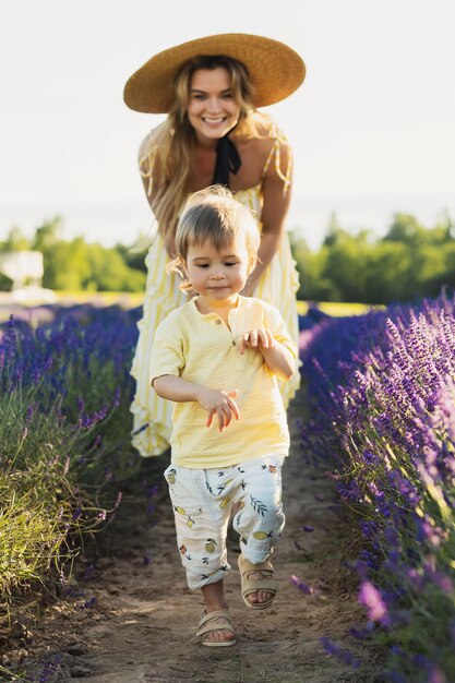 Hermosa mujer joven y su lindo hijito en el campo de lavanda