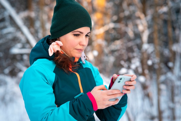 Foto hermosa mujer joven con su teléfono inteligente al aire libre en invierno día soleado con nieve