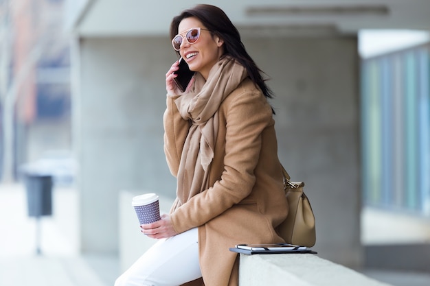 Hermosa mujer joven con su teléfono móvil en la calle.