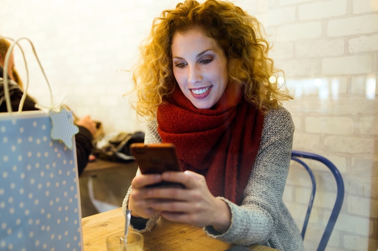 Foto hermosa mujer joven con su teléfono móvil en la tienda de café.