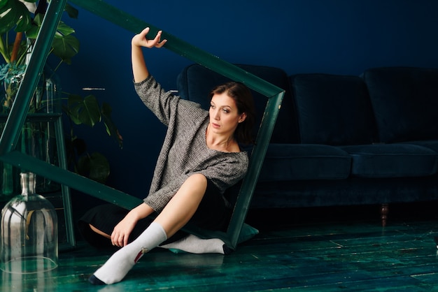 Foto hermosa mujer joven en suéter gris en casa