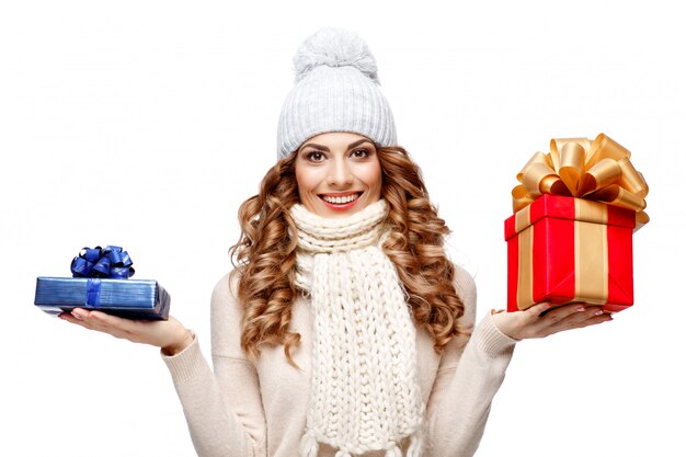 Hermosa mujer joven en suéter de lana tejida sonriendo sosteniendo cajas de regalo