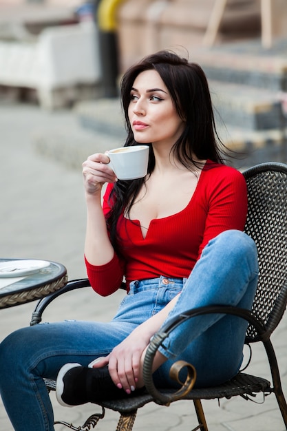 Hermosa mujer joven con taza de café en las calles de la ciudad