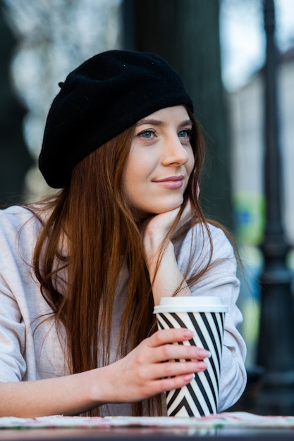 Hermosa mujer joven con taza de café en las calles de la ciudad