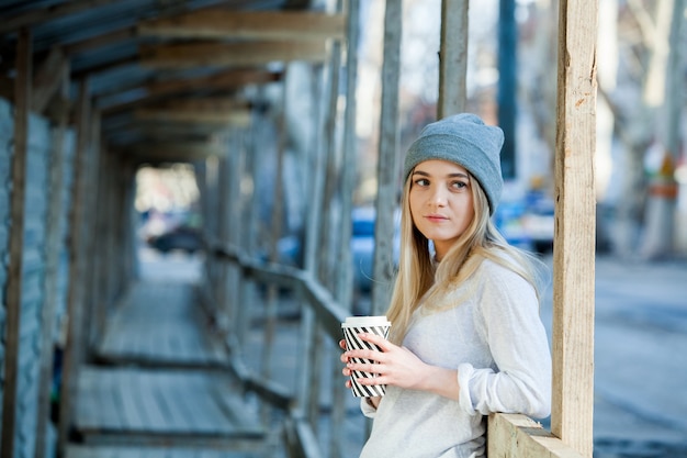 Hermosa mujer joven con taza de café en las calles de la ciudad