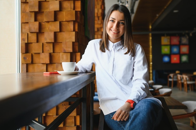 Hermosa mujer joven con una taza de té en un café