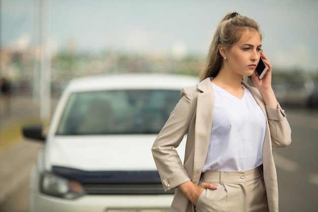 hermosa mujer joven con teléfono cerca del coche