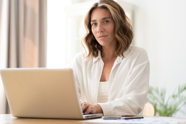 Hermosa mujer joven trabajando desde casa en la computadora portátil.