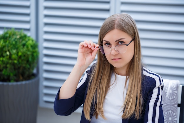 Hermosa mujer joven trabajando en una computadora portátil y sonriendo mientras está sentado al aire libre en un café. Mujer joven con ordenador portátil para el trabajo. Freelancer mujer trabajando en un portátil en un café al aire libre.