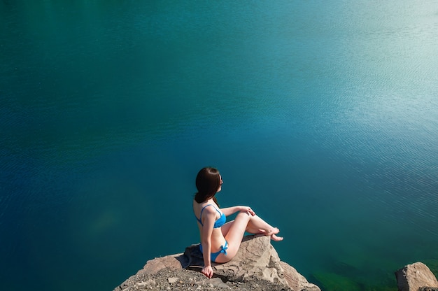 Hermosa mujer joven en traje de baño de pie en el lago por la mañana. Concepto de turismo. Concepto de verano