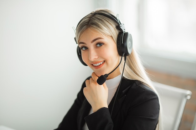 Hermosa mujer joven en un traje en la oficina en la mesa con auriculares