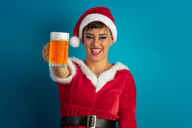 Foto hermosa mujer joven con traje de papá noel y sombrero sosteniendo un vaso de cerveza y tema de navidad