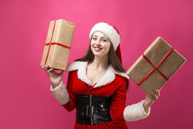 Hermosa mujer joven en traje de Santa Claus contra el fondo rojo.