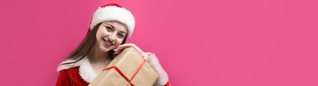 Hermosa mujer joven en traje de Santa Claus contra el fondo rojo.