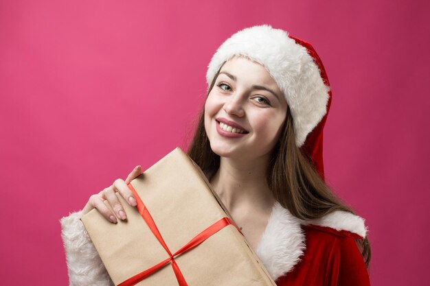 Hermosa mujer joven en traje de Santa Claus contra el fondo rojo.