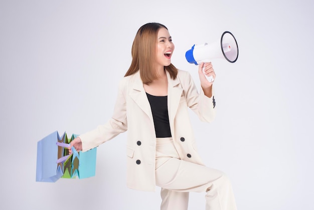 Hermosa mujer joven en traje sosteniendo coloridas bolsas de la compra sobre fondo blanco studio