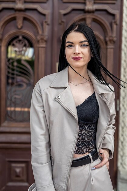 Hermosa mujer joven usa traje blanco de moda contra la vieja puerta de madera