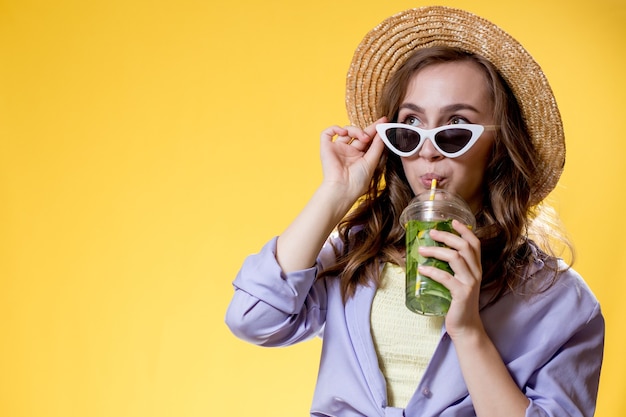 Hermosa mujer joven con vaso de plástico de cóctel fresco