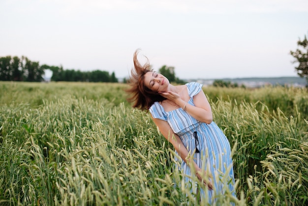 Hermosa mujer joven en verano en un campo de trigo