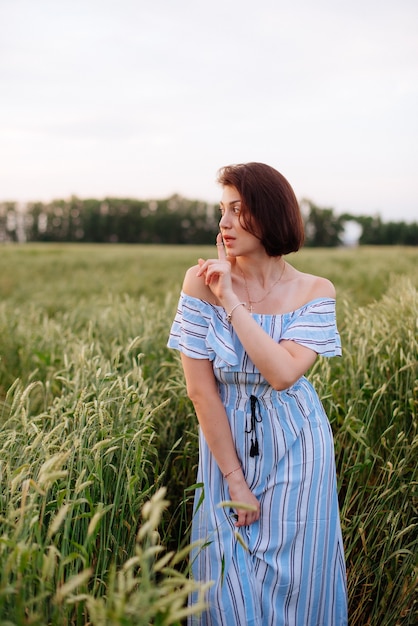 Hermosa mujer joven en verano en un campo de trigo