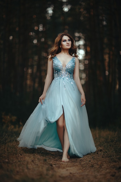 Hermosa mujer joven con vestido blanco en el bosque