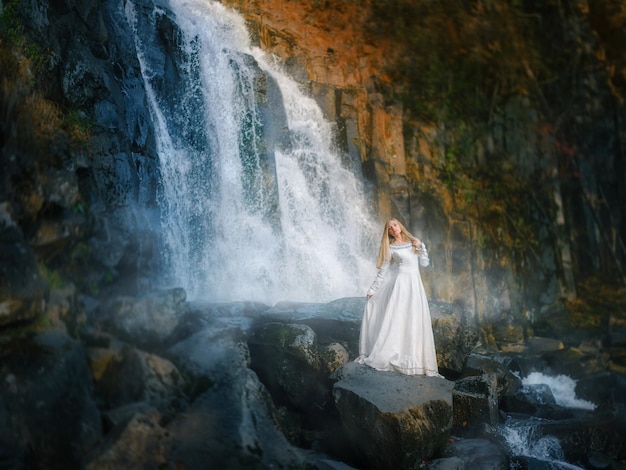 Hermosa mujer joven con un vestido blanco camina en medio de un bosque