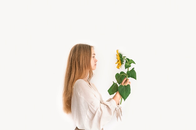 Hermosa mujer joven en vestido de lino con girasol en blanco