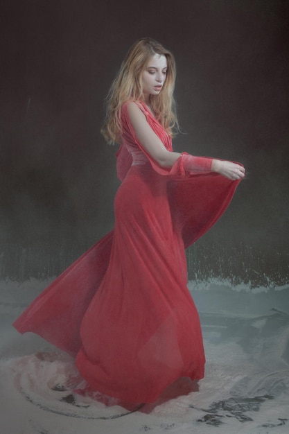 Hermosa mujer joven en vestido rojo bailando en harina
