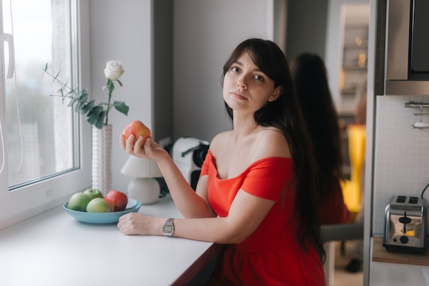 Hermosa mujer joven en vestido rojo sosteniendo una gran manzana en su mano