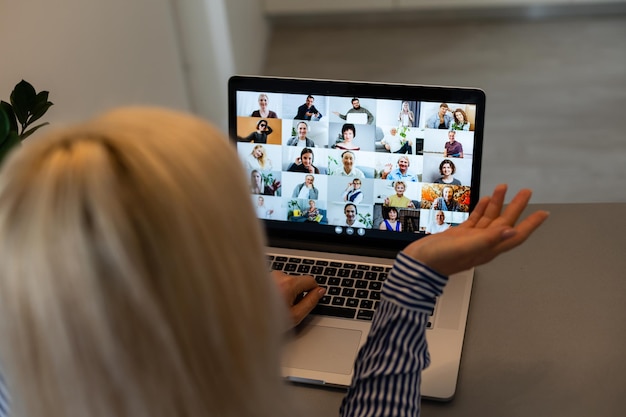 Hermosa mujer joven con videoconferencia a través de computadora. Llamada grupal. Oficina en casa. Quédese en casa y trabaje desde el concepto de casa durante la pandemia de coronavirus