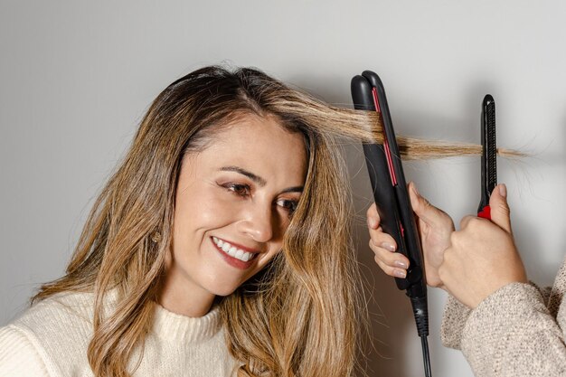 Hermosa mujer latina sonriendo mientras un estilista profesional le peina el cabello