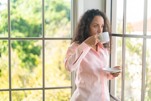 Hermosa mujer latina tomando café en la mañana