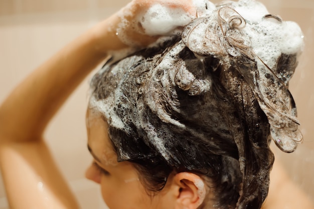 Hermosa mujer lavarse el cabello con champú