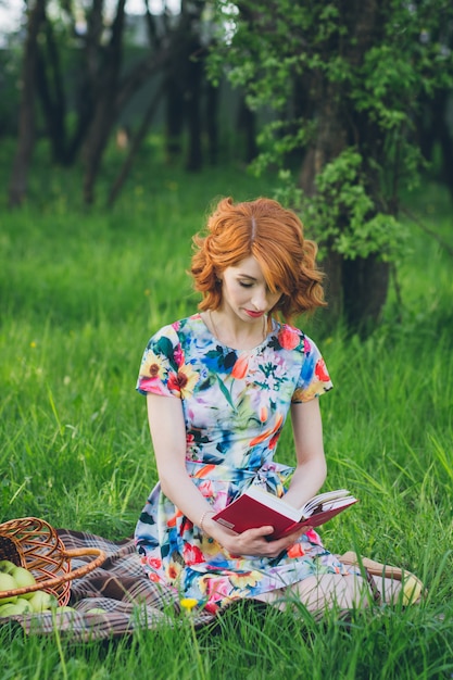 Hermosa mujer leyendo un libro en el jardín de primavera