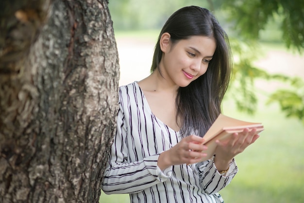 Hermosa mujer leyendo un libro en el parque verde