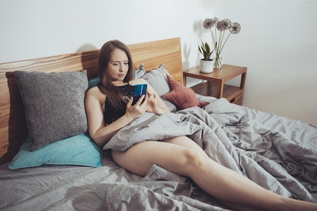 Hermosa mujer leyendo sentada en una cama cómoda