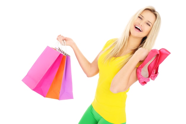 Una hermosa mujer llevando bolsas de la compra y tacones sobre fondo blanco.