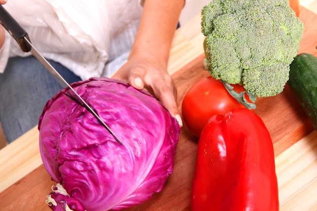 Una hermosa mujer madura cortando verduras en la cocina.