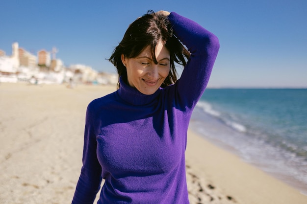 Hermosa mujer madura feliz disfrutando de un soleado día de invierno en la playa